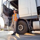 Kierowca z prawem jazdy na ciężarówkę relaksujący się przy pojeździe na parkingu.