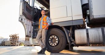 Kierowca z prawem jazdy na ciężarówkę relaksujący się przy pojeździe na parkingu.