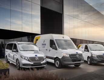 Zdjęcie z boku na samochody dostawcze przed budynkiem