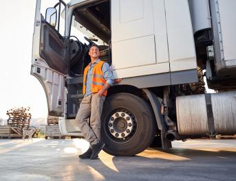 Kierowca z prawem jazdy na ciężarówkę relaksujący się przy pojeździe na parkingu.