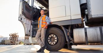 Kierowca z prawem jazdy na ciężarówkę relaksujący się przy pojeździe na parkingu.